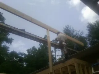 Carpenter setting a ridge beam over a new addition frame — Ice Dam Removal by Roofing Brothers in Dundee